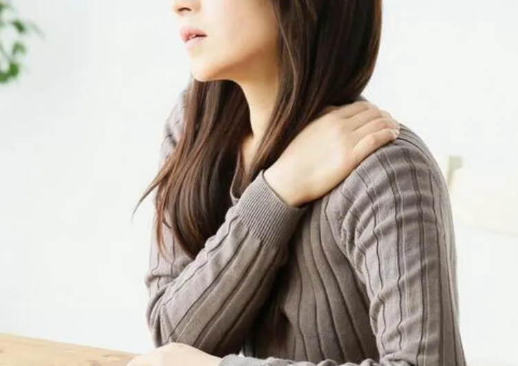 肩を抑える女性
